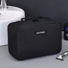 A black portable waterproof travel toiletry bag resting on a gray surface next to a white sink.