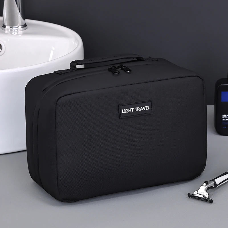 A black portable waterproof travel toiletry bag resting on a gray surface next to a white sink.
