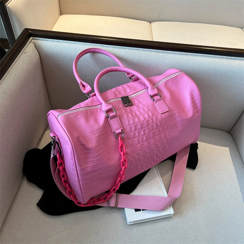 A pink crocodile grain PU leather travel duffle bag resting in a light-colored box.