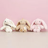 Three plush rabbit toys in white, beige, and pink colors displayed against a light background.