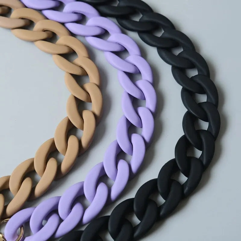 Three strands of adjustable long bag straps in beige, purple, and black coiled together.