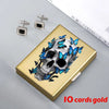 A gold card holder featuring a skull design with blue butterfly accents and small silver earrings.
