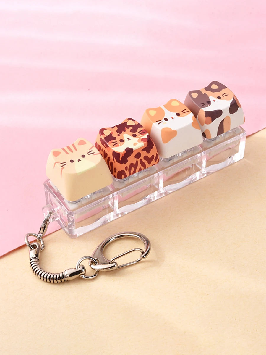 A set of acrylic cat-themed keycaps and fidget toys arranged in a clear plastic holder.