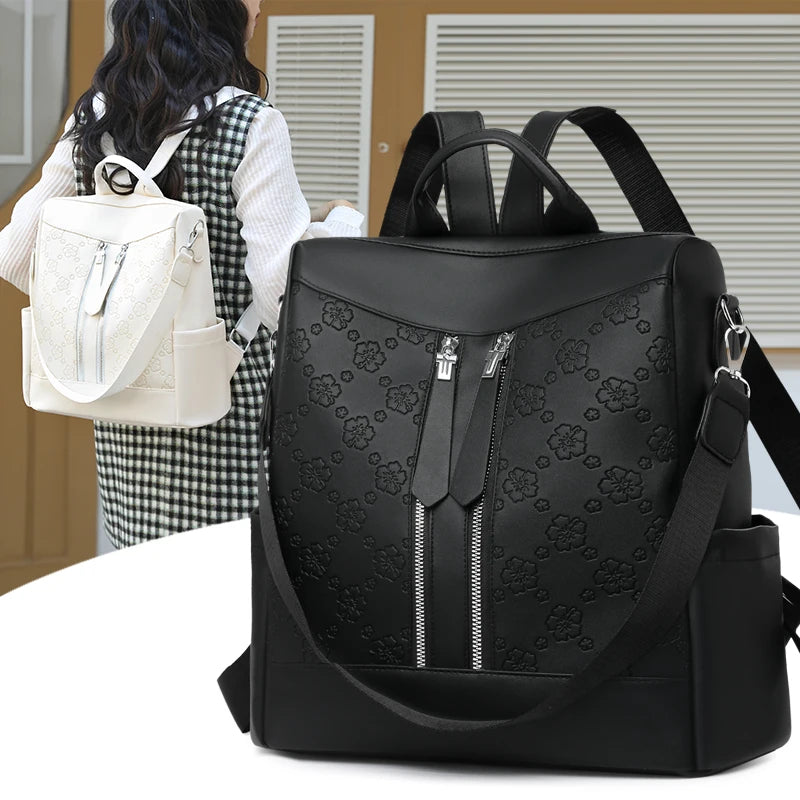 Black leather anti-theft women's backpack with floral pattern shown against a light background.
