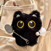 Colgante de gato negro de peluche con ojos amarillos grandes sujeto a una bolsa de tela blanca.