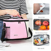 Pink and white insulated reusable lunch bag with a mesh pocket and adjustable strap shown next to fresh fruit.