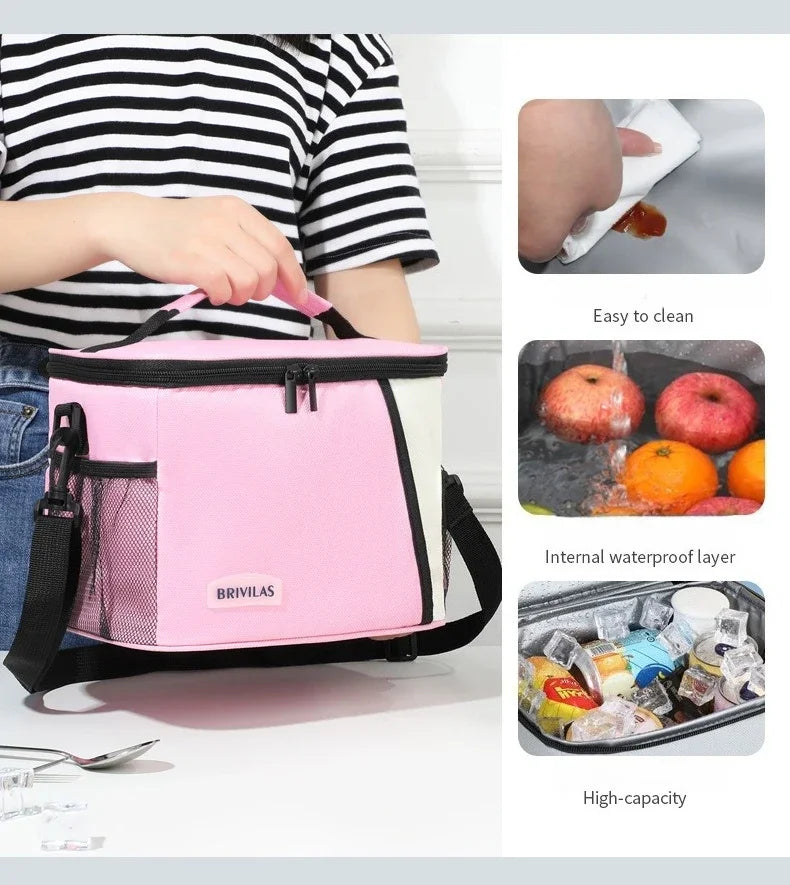 Pink and white insulated reusable lunch bag with a mesh pocket and adjustable strap shown next to fresh fruit.