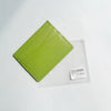 Porte-cartes en cuir véritable vert lime avec une pochette en plastique transparent et une étiquette blanche.