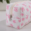 Bolsa acolchada blanca para maquillaje con estampado de lazo rosa y cremallera plateada.