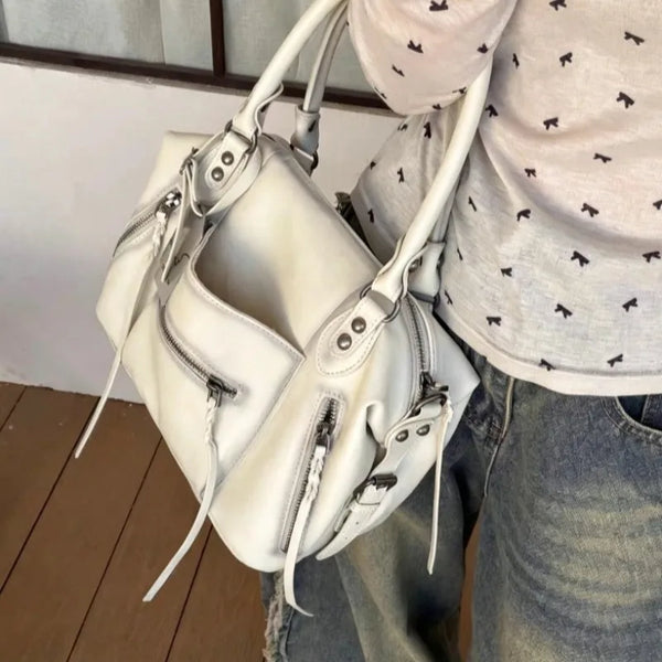 A white retro motorcycle PU leather crossbody shoulder bag is shown being held by a person.