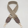 A beige and black checkered braided nylon bag strap with metal hooks.
