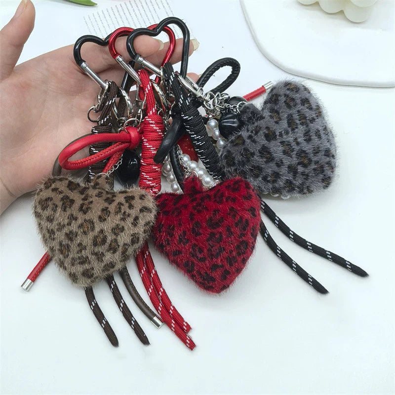 A collection of leopard print faux fur charm keychains in various shades of brown and red.