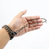 A hand is holding a handwoven paracord camera wrist strap with a dark green and brown pattern.