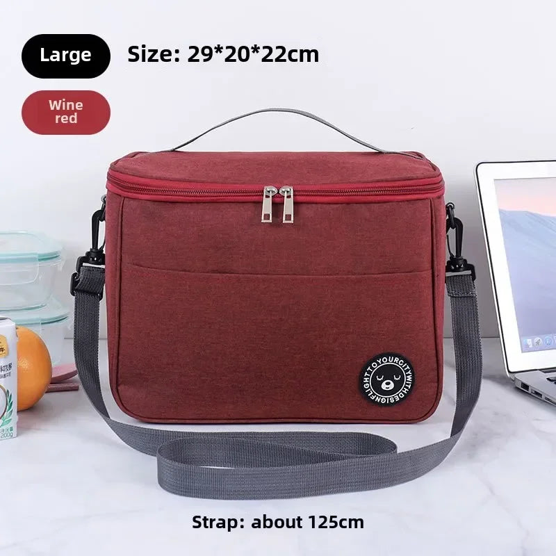 A maroon insulated portable lunch bag with a gray strap is shown on a white surface.