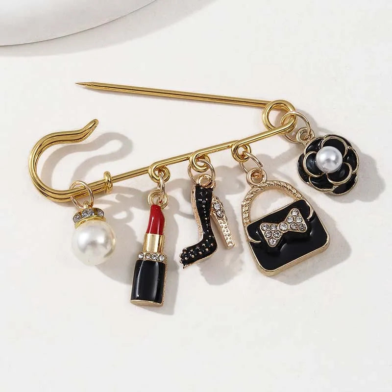 Gold-toned alloy brooch pin featuring black and white accents, including pearl and glitter details.