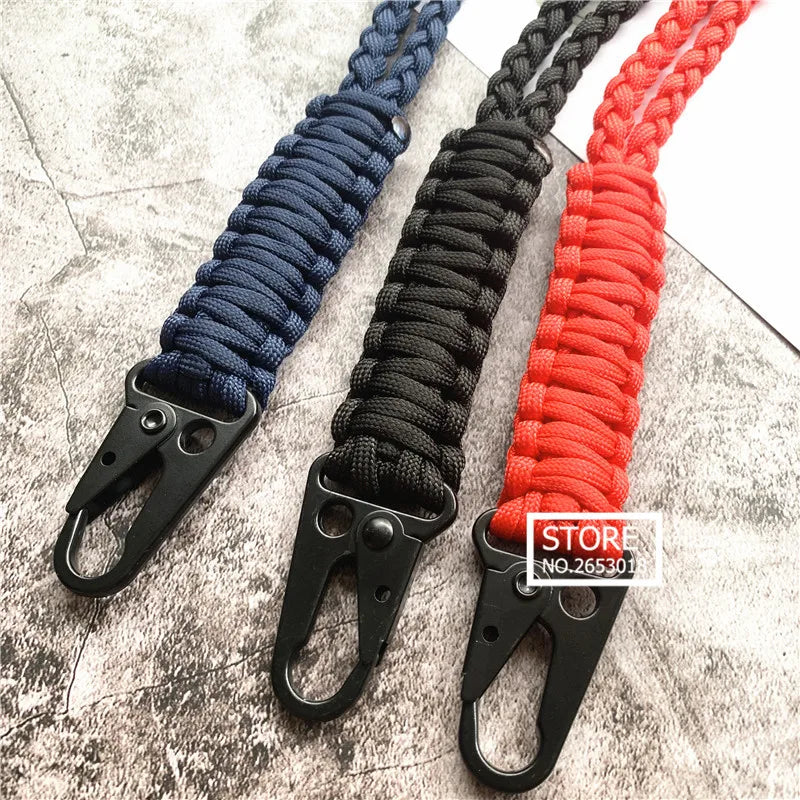 Three hand-woven nylon lanyards in blue, black, and red with metal hooks displayed on a gray surface.