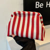A red and white striped crochet tote bag with a shell accent is held by a person.