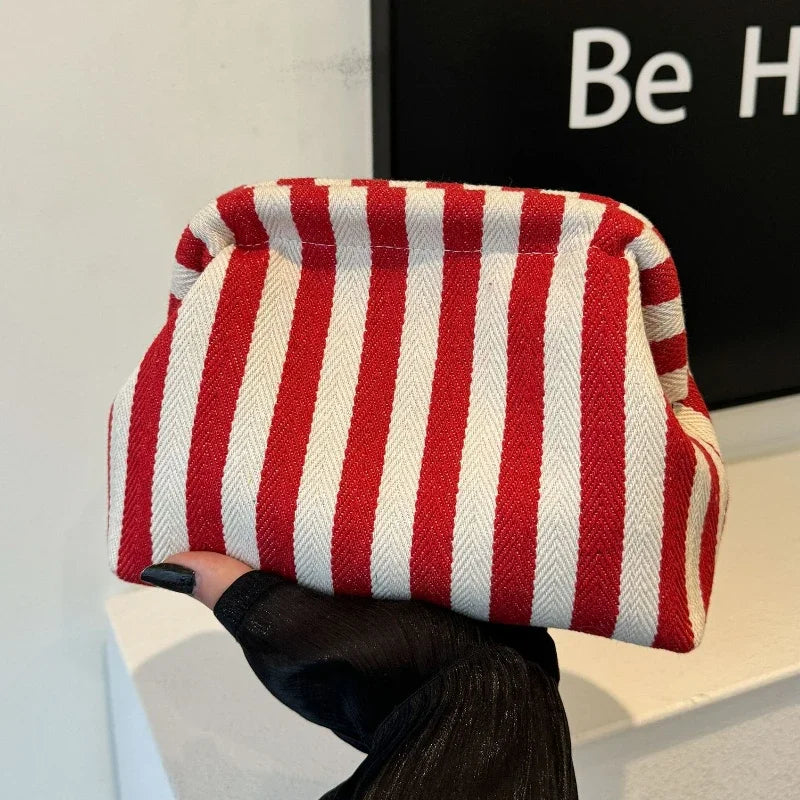 A red and white striped crochet tote bag with a shell accent is held by a person.