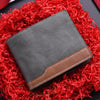 A grey PU leather men's wallet with a brown accent, resting on a bed of bright red shredded material.