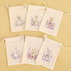 A set of six natural linen drawstring gift bags featuring delicate illustrations of rabbits and purple flowers.