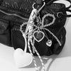 Black leather bag with a white bow key chain charm and heart pendant
