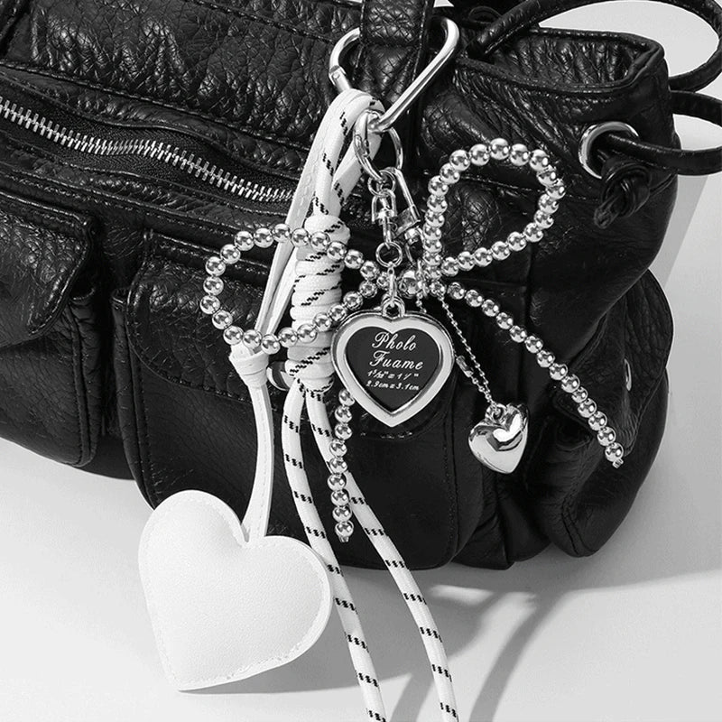 Black leather bag with a white bow key chain charm and heart pendant