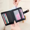 A black minimalist wallet with a gold charm is shown being held by hands, displaying various cards and IDs.