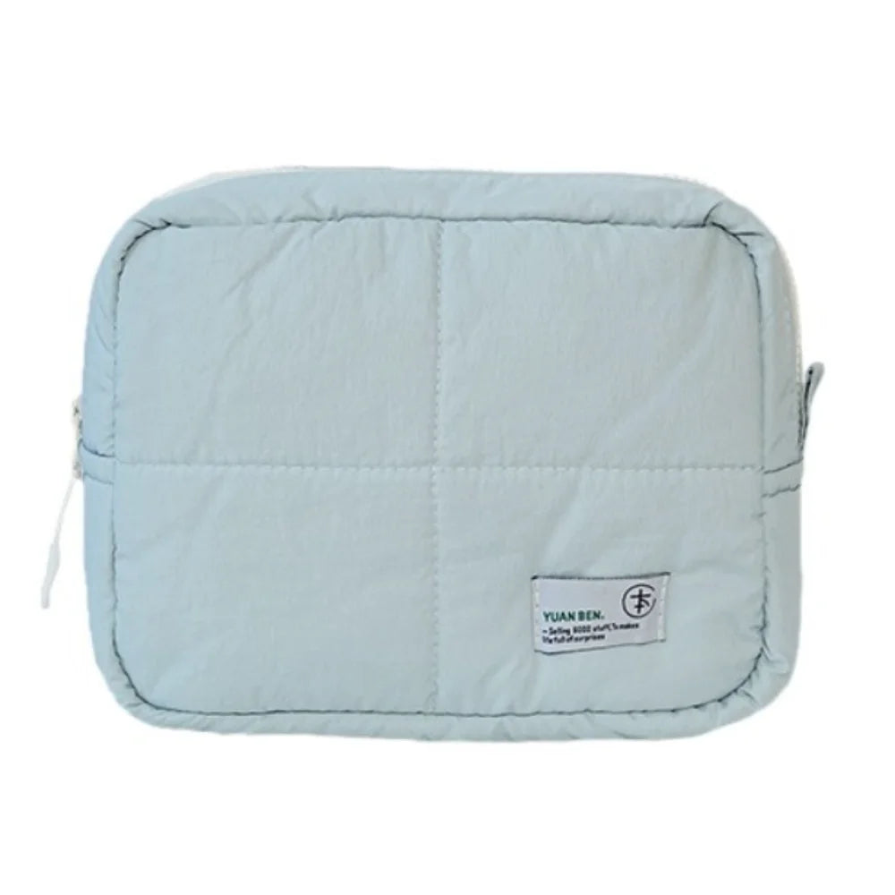 Light blue aesthetic quilted puffer makeup bag with a small logo tag