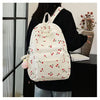 A white corduroy fashion backpack with a floral pattern and adjustable strap is worn by a person.