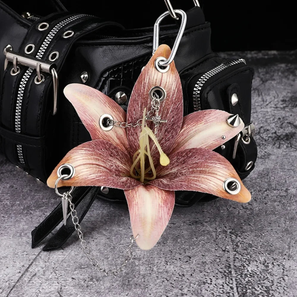 A realistic orchid flower keychain with pink and white petals attached to a black leather bag.