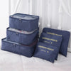 A set of navy blue laundry pouches and storage boxes for travel organization displayed on a white surface.