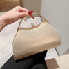 A hand holds a beige pleated glitter evening handbag with a top handle and chain strap.