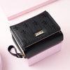 Black compact PU leather women's wallet with a zippered closure and decorative floral embossing