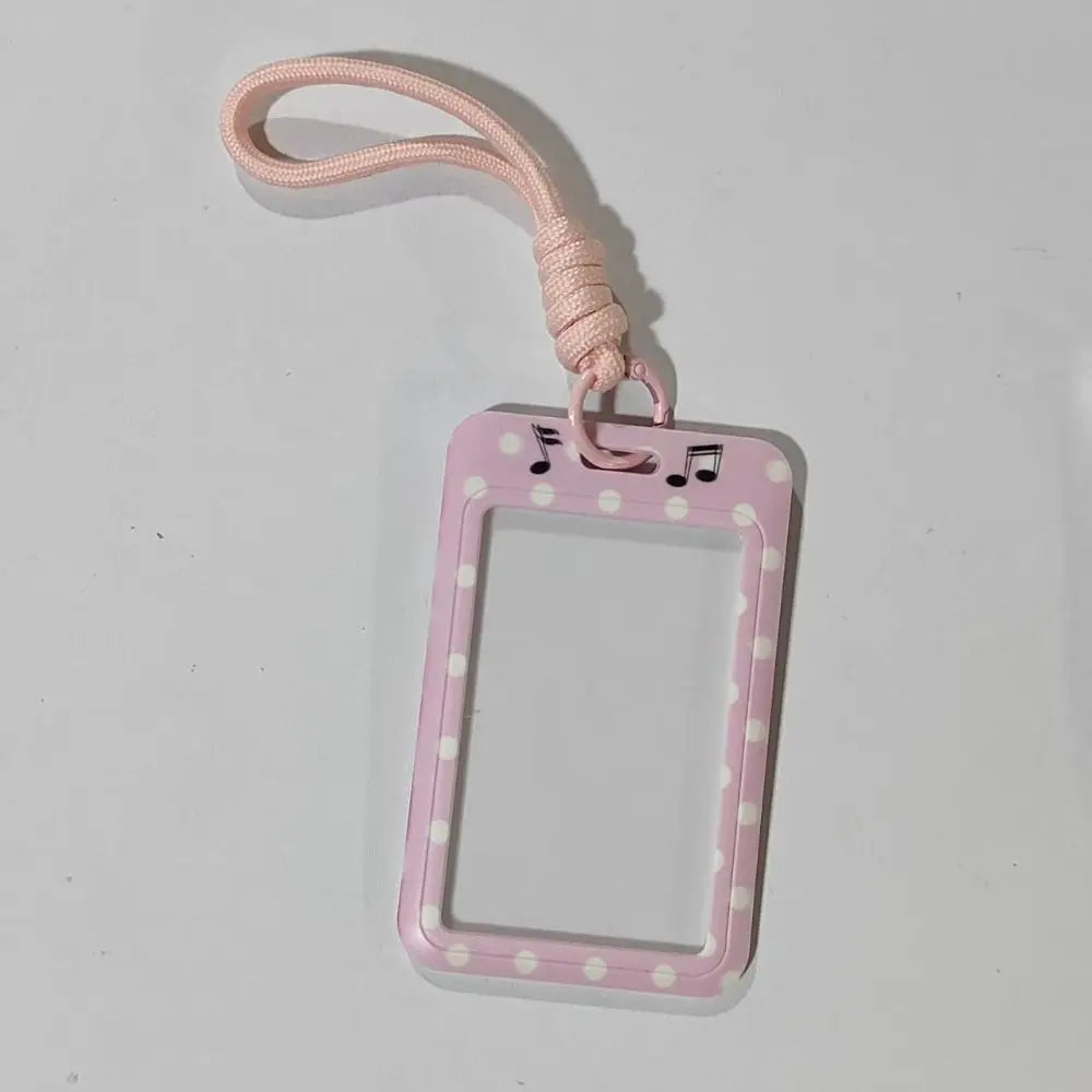 A pink polka dot card holder with a pink lanyard is shown against a white background.