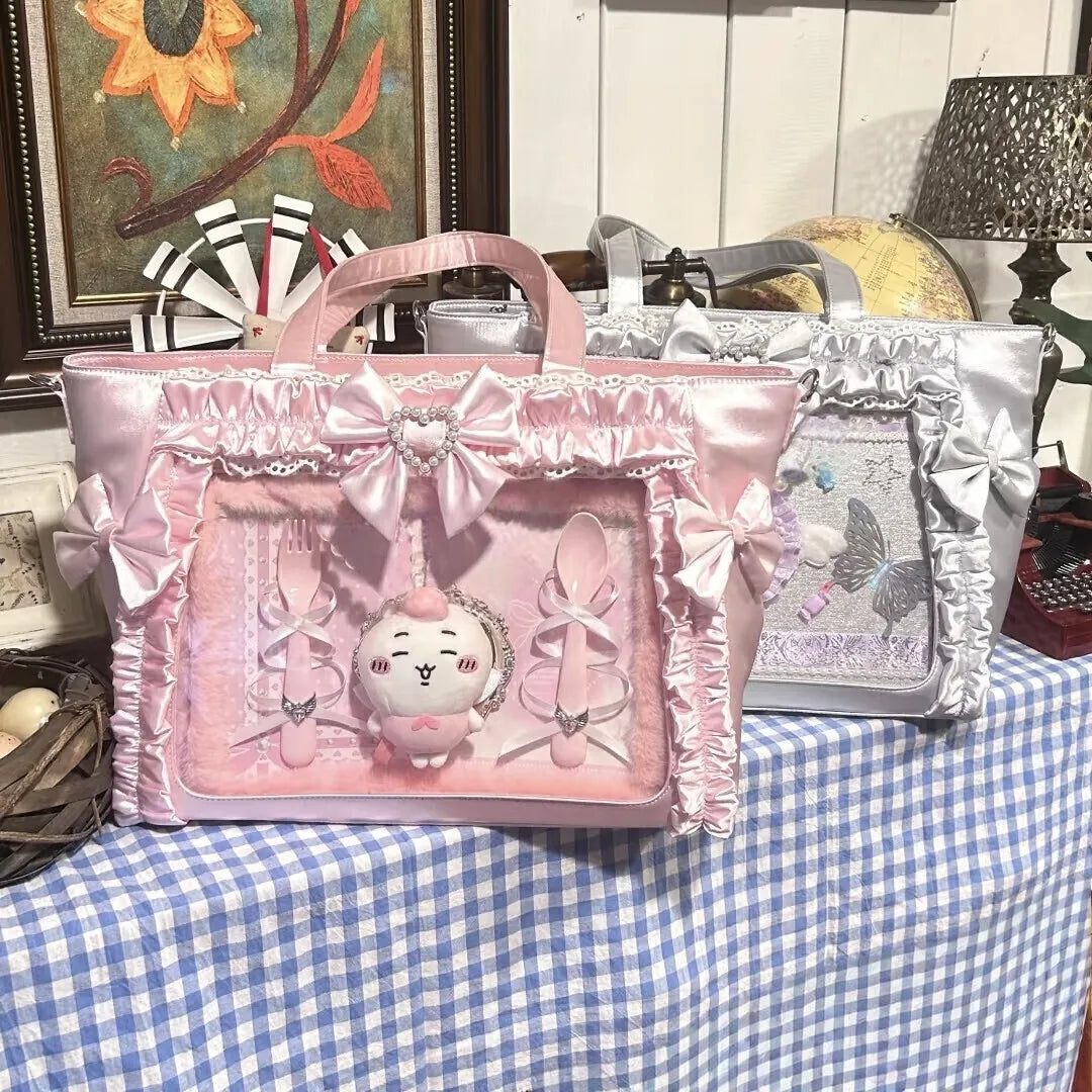 A pink transparent shoulder tote bag decorated with lace and bows, displayed on a checkered cloth.