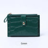A dark green mini crocodile pattern leather card holder with a zipper closure.