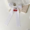 A white lace bow with pearl accents and a red bead keychain tied in a bow knot