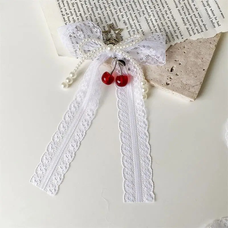 A white lace bow with pearl accents and a red bead keychain tied in a bow knot