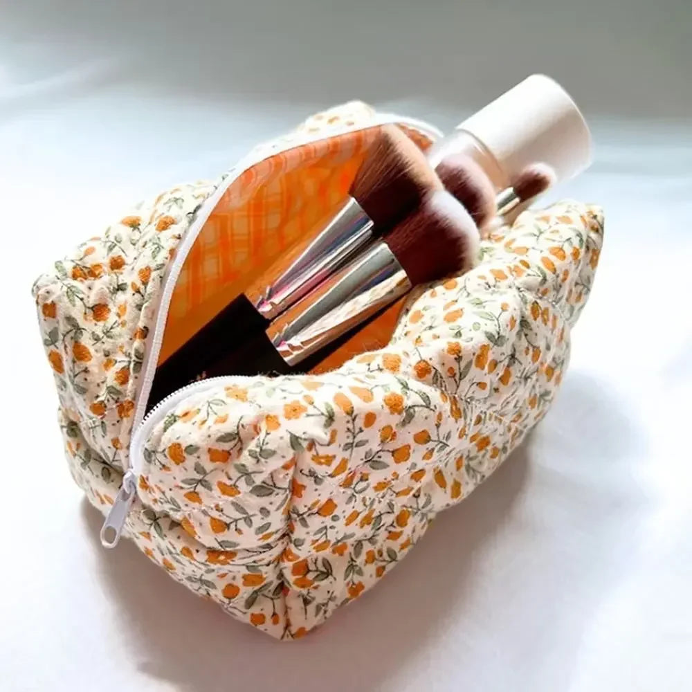 Bolsa de almacenamiento con cremallera acolchada y floral para pinceles de maquillaje.