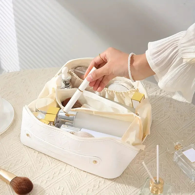 A hand is opening a vintage floral waterproof makeup tote bag revealing various beauty products.