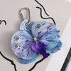 A realistic phalaenopsis orchid flower keychain with blue and purple petals attached to a silver keyring.