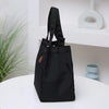 A black durable aluminum foil insulated lunch bag resting on a white shelf.