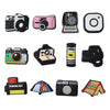 A collection of decorative shoe charms and pins for clogs and sandals, including camera-themed accessories.