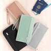Collection de porte-monnaie de voyage colorés, dont un organisateur rose, vert et noir, et un passeport.