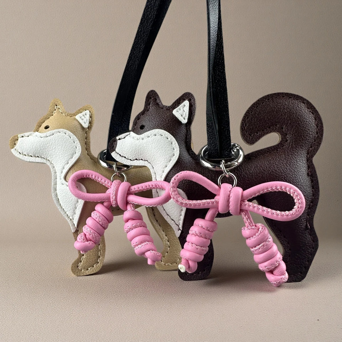 Un adorno con silueta de perro Shiba Inu en cuero beige y blanco con un lazo de cuero trenzado rosa.