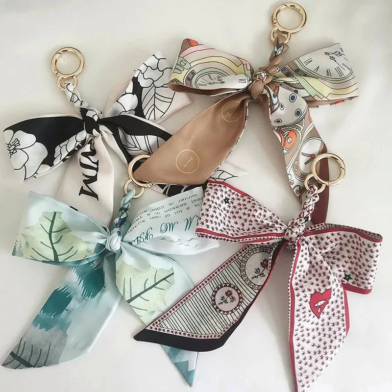 Colección de elegantes lazos de cinta de seda atados en llaveros con telas florales y estampadas.