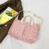 A pink canvas tote bag with a strawberry pattern is shown next to a green jacket and a tray of white tulips.