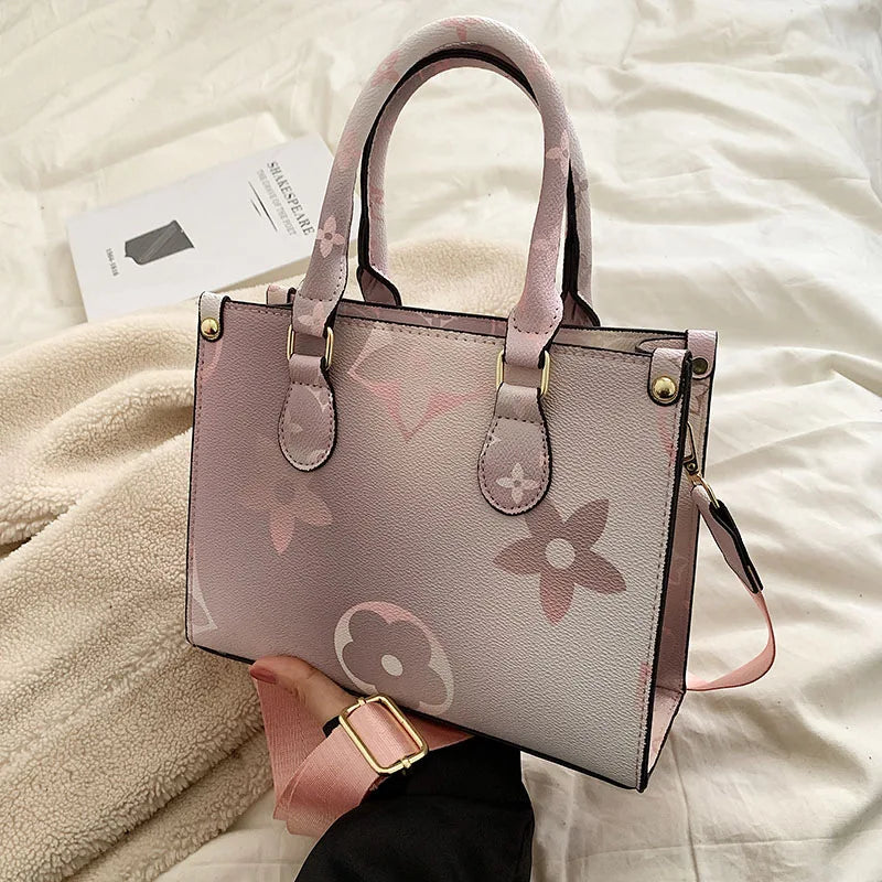 A light pink ladies' shoulder tote bag with a floral pattern resting on a cream-colored blanket.