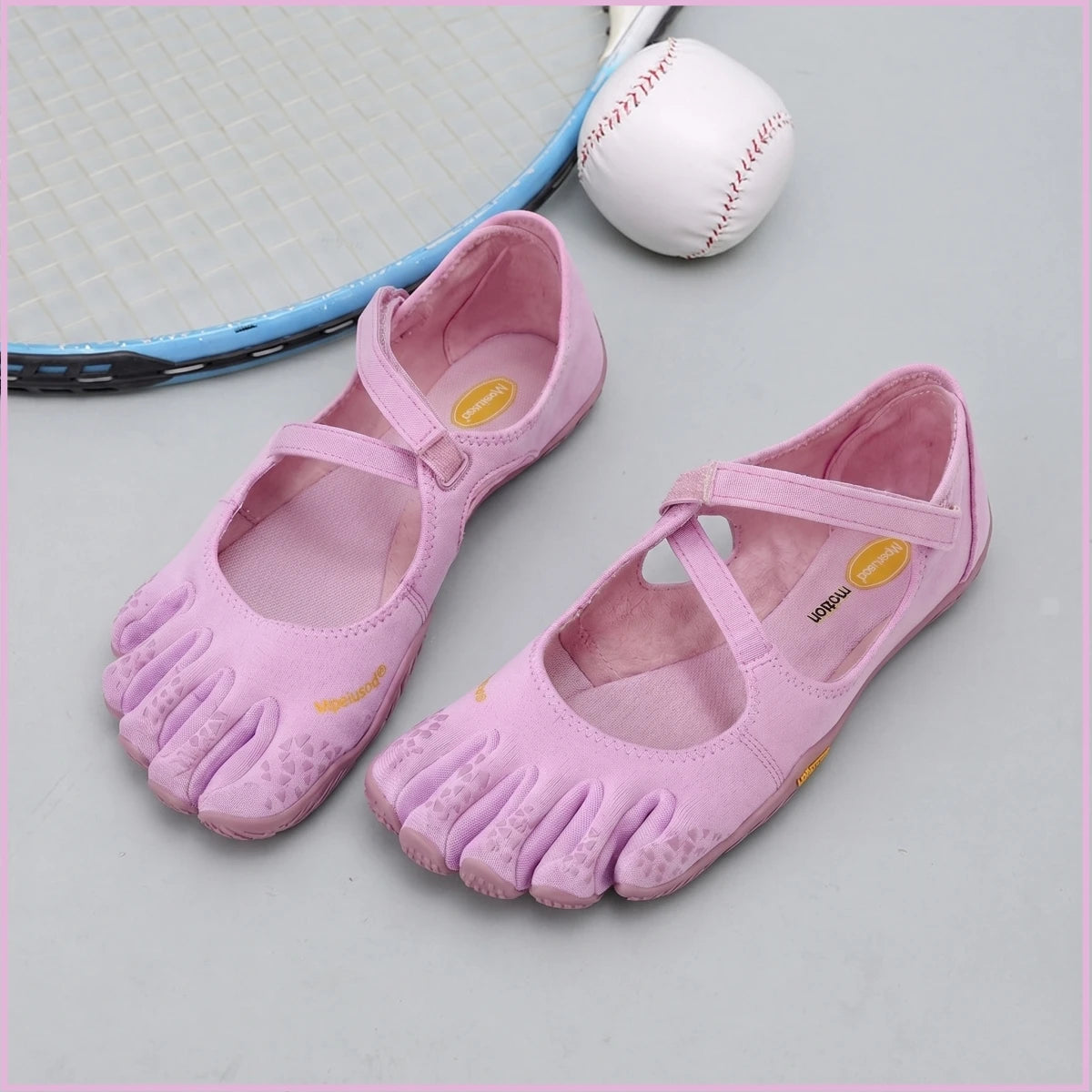 Pink women's barefoot five-toe shoes with an adjustable strap next to a baseball.