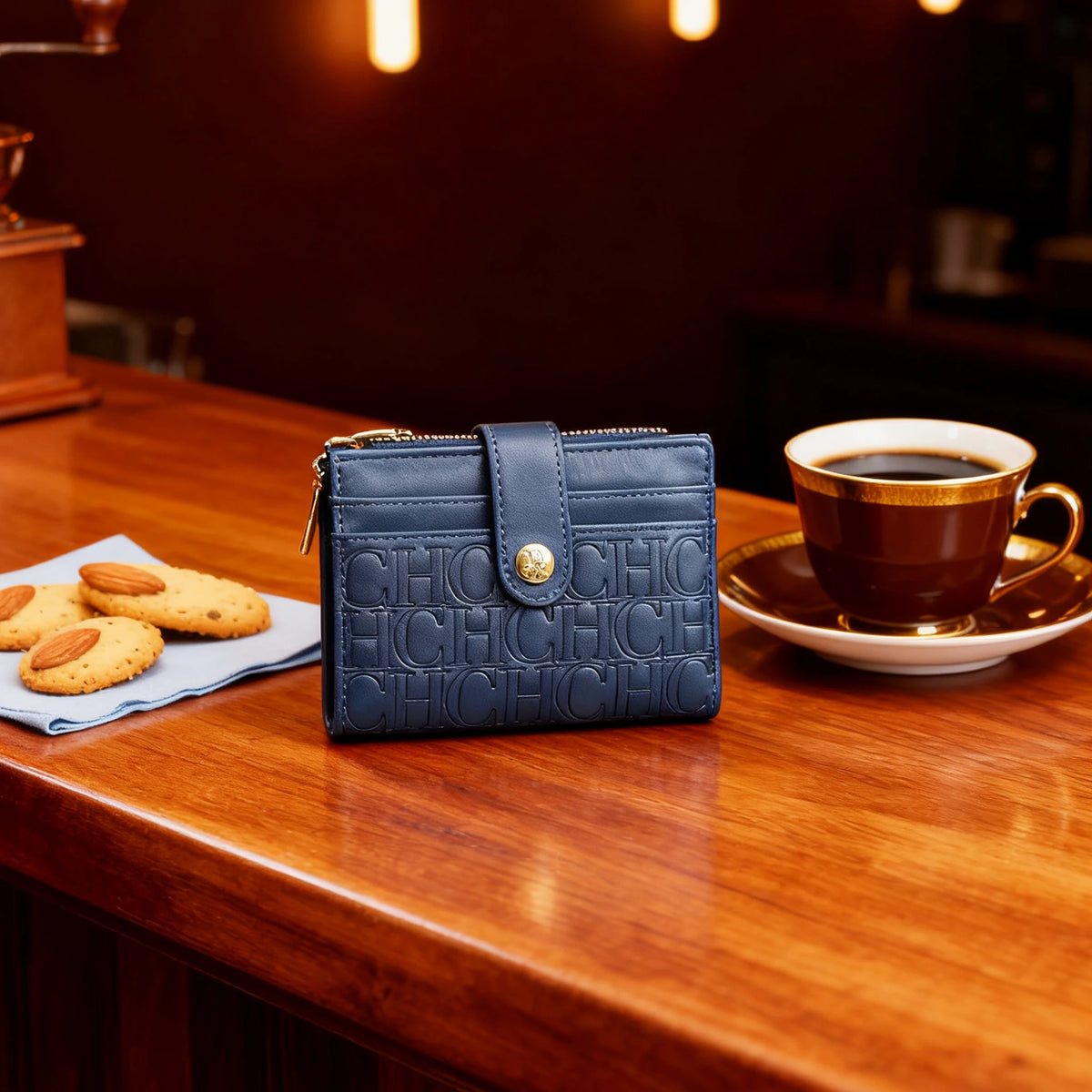 A dark blue classic square folding wallet rests on a wooden table next to a cup of coffee.